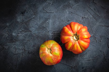 Foto de Rojo acanalado tomate cuore di bue en un fondo oscuro vista superior - Imagen libre de derechos