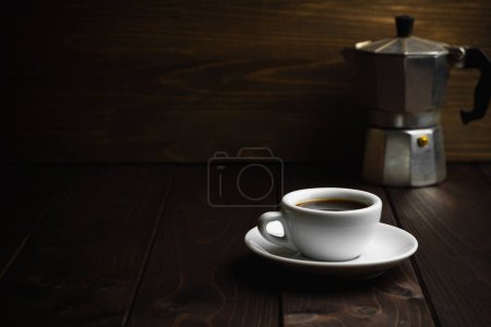 Taza blanca de café con colador de café de metal viejo sobre fondo de madera oscura