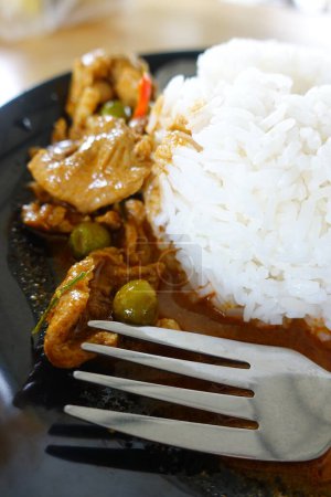 Photo for Recipe for Chicken Curry (Panang Kai) with jasmin rice in black dish on wooden table. Thai cuisine Curry with peanuts, coconut, and meat. Thai style fast food - Royalty Free Image
