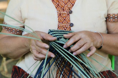 Téléchargez les photos : Une main de femme thaïlandaise tisse un étui à panier ancestral en bambou. Les gens font la démonstration de tissage d'un panier traditionnel en bambou - en image libre de droit