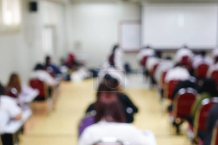 Photo for Blurred abstract background of examination room with undergraduate students inside. Blurred view of a student doing the final test in the exam room. Blurry view of study chairs in university. - Royalty Free Image