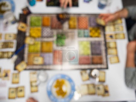 defocused board game from above with people playing food and drink