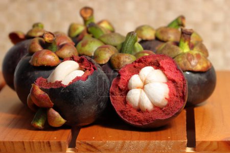 Téléchargez les photos : Mangoustan sur fond en bois. Fruits de prévention du cancer. Mangoustan violet avec noyau juteux - en image libre de droit