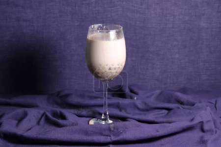 Homemade Milk Bubble Tea. Pouring milk tea in drinking glass with tasty popular taiwan tapioca pearl bubble on bright marble table. Recipe concept