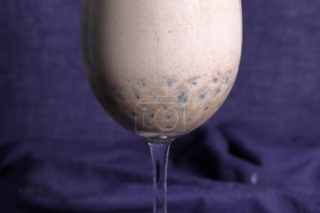 Homemade Milk Bubble Tea. Pouring milk tea in drinking glass with tasty popular taiwan tapioca pearl bubble on bright marble table. Recipe concept