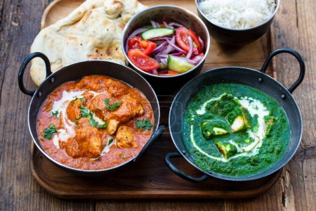 Photo for Butter chicken, saag paneer, toamto salad and naan bread - Royalty Free Image