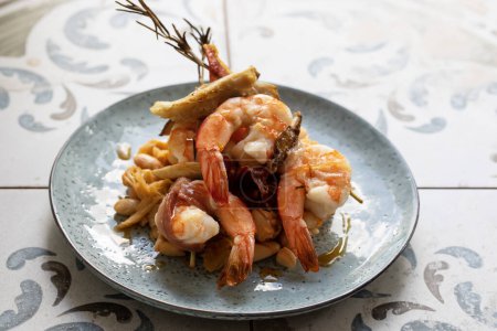 Téléchargez les photos : Brochettes de romarin aux crevettes grillées, champignons et jambon de parme aux haricots et poireaux - en image libre de droit