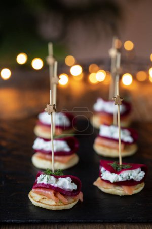 Photo for Christmas canapes with blinis with salmon, pickled beetroot and goat cheese - Royalty Free Image