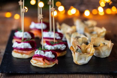 Photo for Christmas canapes with blinis with salmon, beetroot and goat cheese and filo pastry cups - Royalty Free Image