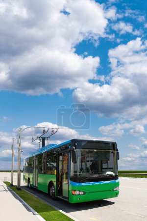 Elektrischer Stadtbus mit Ladestation vor dem Hintergrund des Stadtbildes. Grüner Verkehr und sauberes Mobilitätskonzept 