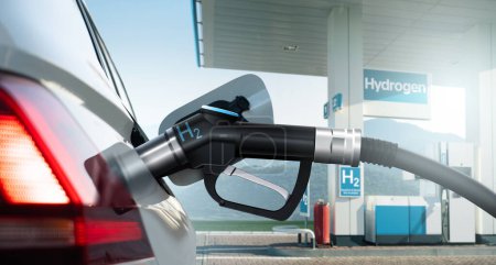 Nahaufnahme eines Brennstoffzellenfahrzeugs mit angeschlossener Wasserstoffbetankungsdüse auf dem Hintergrund einer H2-Tankstelle. Sauberes Mobilitätskonzept