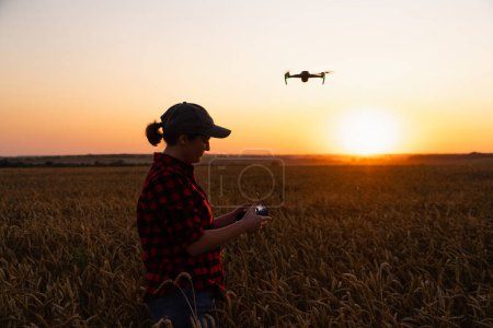 Farmer controls drone sprayer with a tablet on a sunset. Smart farming and precision agriculture