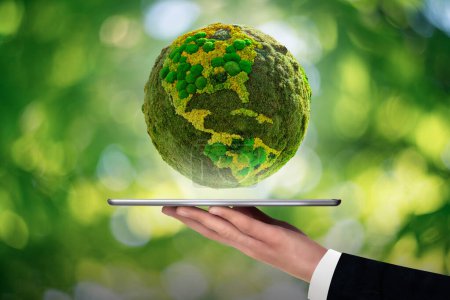 A man is holding a digital tablet. Above this green planet Earth. Symbol of sustainable development and renewable energy