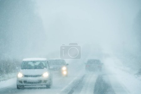 Auto fährt im Schneesturm auf winterlicher Straße.