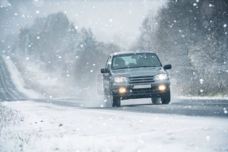 Auto fährt im Schneesturm auf winterlicher Straße.