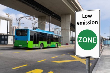 Road sign Low emission ZONE on a background of green electric buses. Clean mobility concept