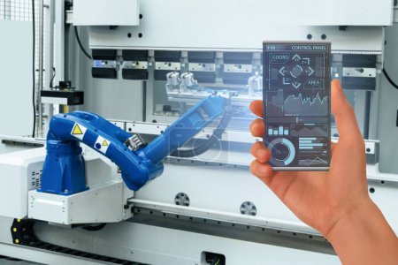 Engineer uses a futuristic transparent smartphone to control robots in a smart factory. Smart industry 4.0 concept..