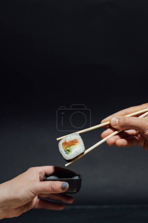 Girls hands hold sushi rolls with bamboo sticks. Japanese traditional food.