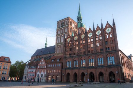 Téléchargez les photos : Stralsund, Allemagne - 30 octobre 2022 : Vue sur la mairie de la ville hanséatique de Stralsund, construite dans le style gothique en brique d'Allemagne du Nord, avec des gens marchant sur la place principale - en image libre de droit