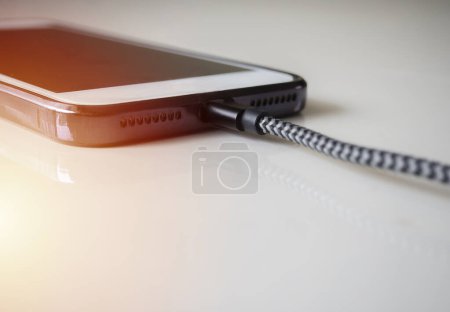 Téléchargez les photos : Smartphone connected to a usb charging cable and fast charging on beige background. Phone fast and quick speed charge. - en image libre de droit