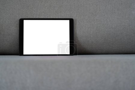 Foto de Tableta negra pantalla blanca en blanco en el sofá de tela gris de diseño moderno. Tecnología Dispositivo de información portátil digital Mockup - Imagen libre de derechos