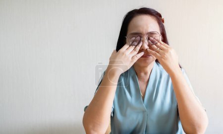 Portrait of Asian woman in glasses rubs her eyes, suffering from tired eyes, ocular diseases concept.
