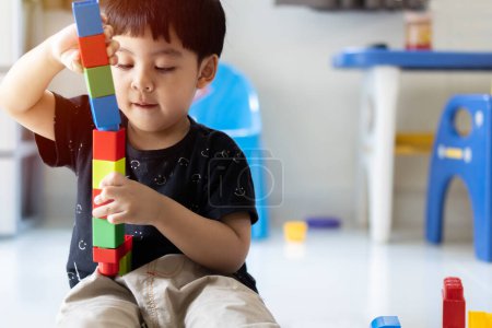 Kleinkind asiatischen niedlichen Jungen spielen kreative Spielzeugblöcke zu Hause. Kreative Kindergartenkinder bauen einen Blockturm. Lernspielzeug für Kleinkind oder Baby.
