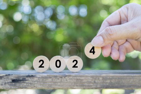 Photo for Close up image of hand puting a wooden circle to 2024 over the nature background. 2024 new year idea concept. - Royalty Free Image