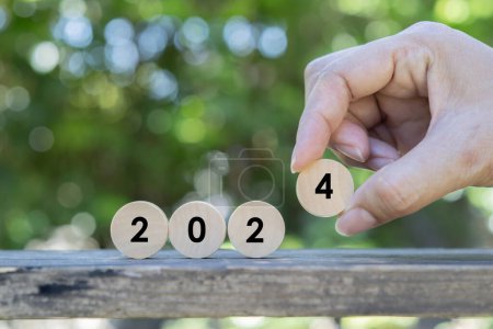 Photo for New year 2024. Close up of hand set the wooden circle number over nature background. New year resolution goal concept - Royalty Free Image