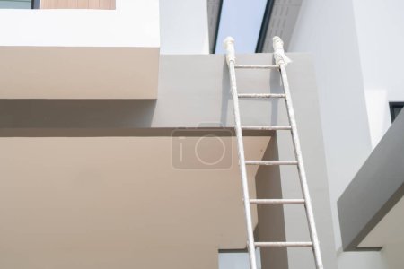 Téléchargez les photos : Échelle pliante métallique près du mur beige à l'extérieur pendant la rénovation de la maison. Espace de copie. - en image libre de droit