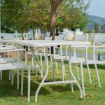  White dining table with chairs in the outdoor garden surround with garden green field. Outdoor dining concept.