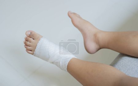 Top view of bandaged feet of a child because of a little accident after falling down. First aid for kids after injury/trauma