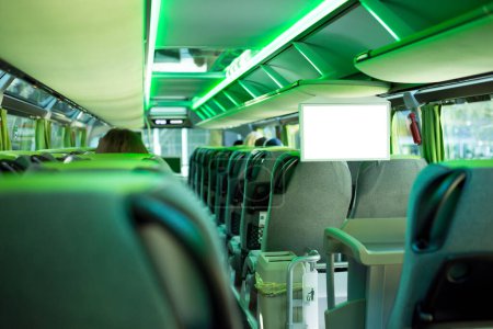 Photo for Row of comfortable seats inside a modern tourist bus with green backlight and big white screen with copy space - Royalty Free Image