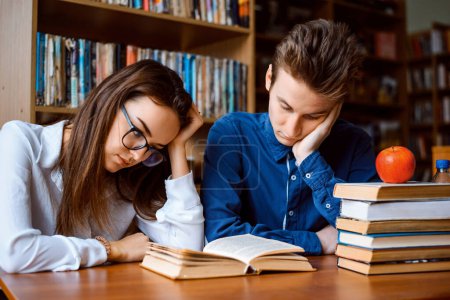 Photo for Male and female students reading book, preparing for classes and feel sick and tired of constant studying, dreaming of weekends and free time - Royalty Free Image