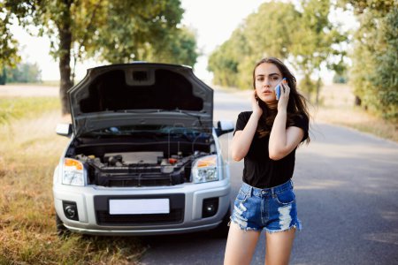 Una mujer llamando a un mecánico después de que su auto se averiara. Chica molesta llegará tarde al destino debido a problemas con su coche