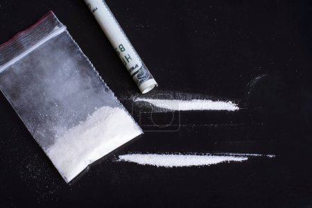 Foto de Pequeña bolsa de plástico con drogas blancas en polvo con dos líneas listas para inhalar por persona drogadicta - Imagen libre de derechos