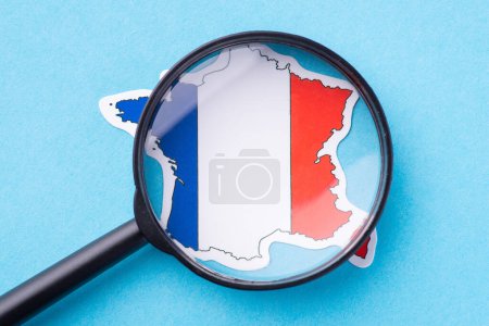 Magnifying glass over a map of France. Concept of geography, traveling, studying the country, exploring.