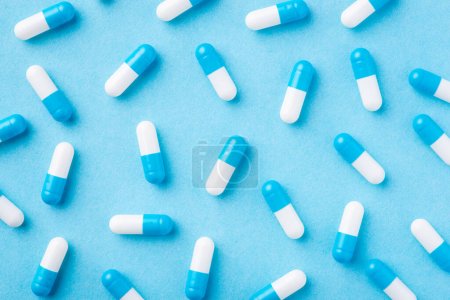Téléchargez les photos : Contexte de nombreuses pilules bleues et blanches sur un fond médical bleu. Concept de médecine, traitement, pharmacie - en image libre de droit