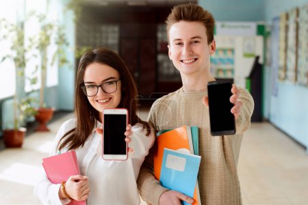 Photo for Young smiling freshers showing screens of their smartphones to the camera happy to receive message about entering desired leading university ready to study hard and achieve high results - Royalty Free Image