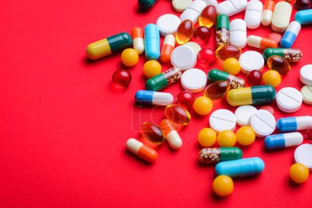 Photo for Background of colorful capsules and pills on red background with copy space. Symbol of medicine - Royalty Free Image