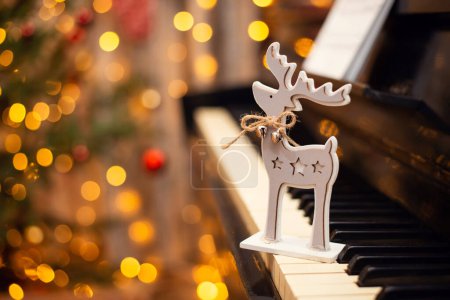 Weihnachtliche Hirschdekoration mit Glöckchen auf der Klaviertastatur. Weihnachtsstimmung