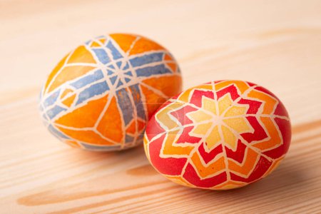Foto de Two coloured Easter eggs on wooden table. Traditional painted eggs with different ornaments and patterns on Easter celebration - Imagen libre de derechos