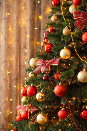 Foto de Close-up vertical shot of decorated Christmas tree. Fir tree in golden and red baubles, lights, celebrating New Year - Imagen libre de derechos