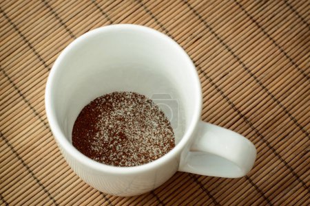 Cup with ground coffee and sugar against a brown bamboo background. Making coffee