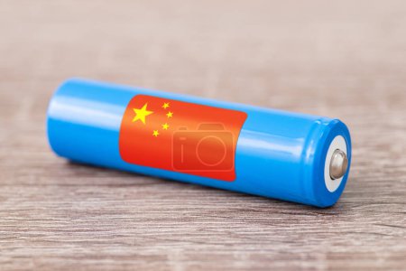 Téléchargez les photos : Gros plan de la batterie li-ion sur table en bois avec drapeau de la Chine - le premier producteur mondial de batteries rechargeables. Concept de production d'accumulateurs en Chine, origine des batteries - en image libre de droit