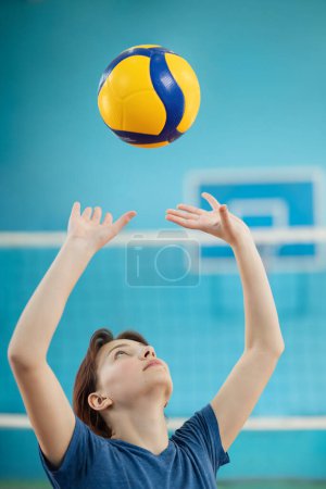 Téléchargez les photos : Jeune fille apprenant des compétences fondamentales pour jouer au volley-ball. Photo en action d'une fille s'entraînant pour passer et régler le volley-ball - en image libre de droit