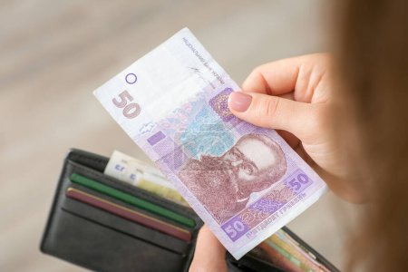 Foto de Mujer pagando por algo con 50 hryvnia. Billete de Hryvnia y un bolso en manos de una chica - Imagen libre de derechos