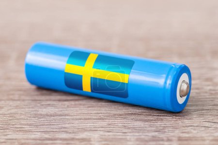 Foto de Batería recargable con bandera de Suecia en la mesa. Origen de la batería, producir acumuladores en Suecia - Imagen libre de derechos