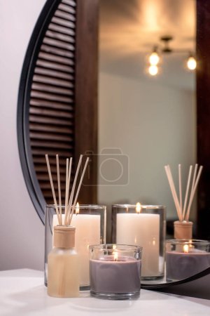 Téléchargez les photos : Air freshener in a glass bottle and scented candles in candle holders. Home atmosphere. Fragrances for the home. - en image libre de droit