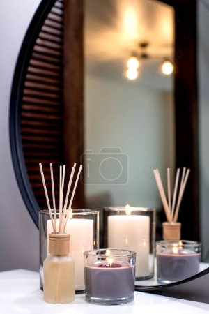 Foto de Air freshener in a glass bottle and scented candles in candle holders. Home atmosphere. Fragrances for the home. - Imagen libre de derechos